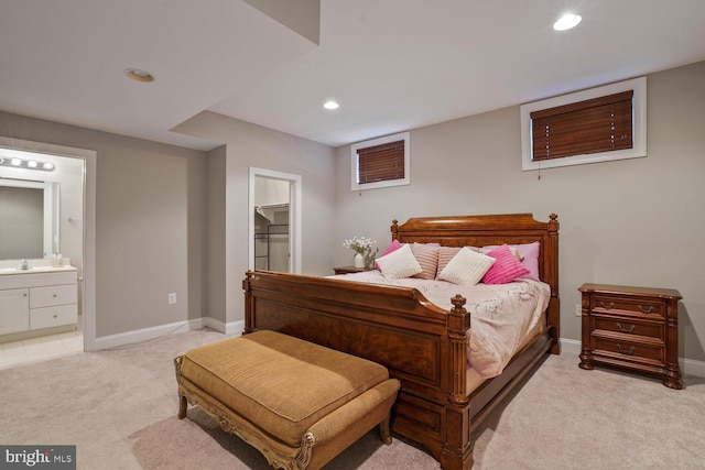bedroom featuring light colored carpet, a sink, recessed lighting, baseboards, and a spacious closet
