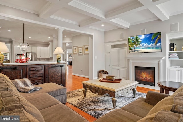 living room featuring light wood-type flooring, coffered ceiling, beam ceiling, a fireplace with flush hearth, and ornamental molding
