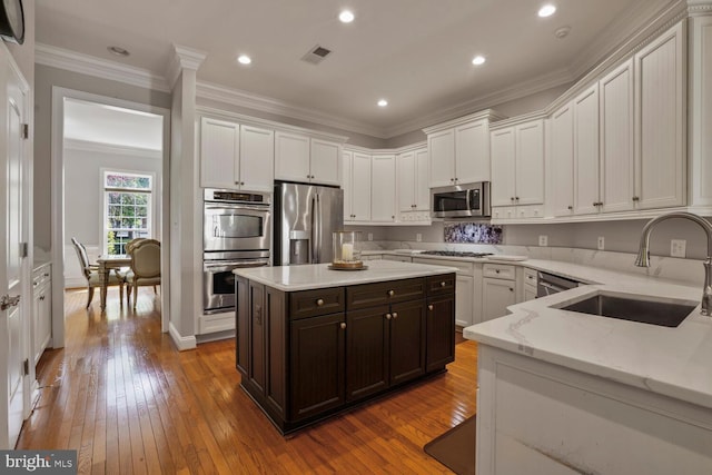 kitchen with a sink, stainless steel appliances, white cabinetry, hardwood / wood-style floors, and dark brown cabinets