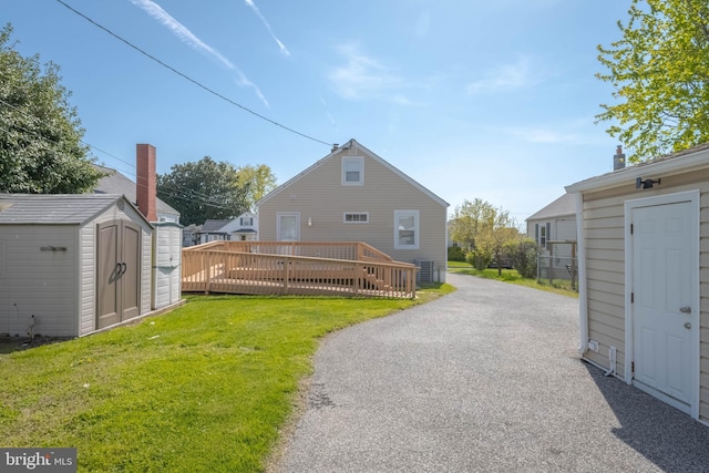 1903 Walnut Ave, Baltimore, MD 21222 - rear view of property featuring driveway, a wooden deck, an outdoor structure, a storage unit, and a yard