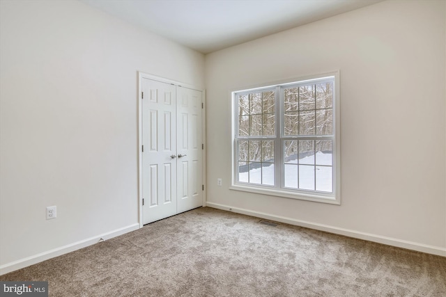 unfurnished bedroom featuring visible vents, carpet flooring, baseboards, and multiple windows
