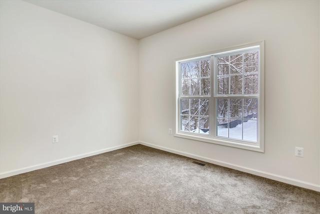 carpeted empty room featuring baseboards and visible vents