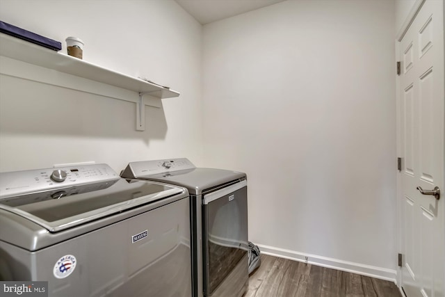washroom with baseboards, laundry area, washing machine and dryer, and wood finished floors