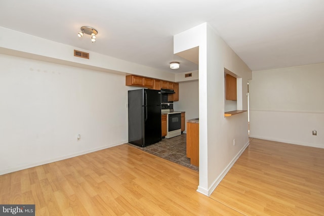 kitchen featuring light wood finished floors, range with electric stovetop, visible vents, and freestanding refrigerator