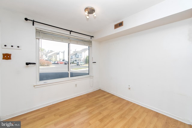 spare room with light wood-style flooring, visible vents, and baseboards