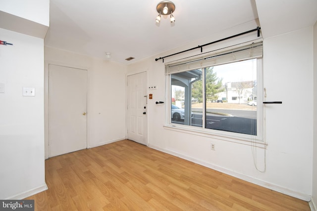empty room with baseboards, wood finished floors, and visible vents