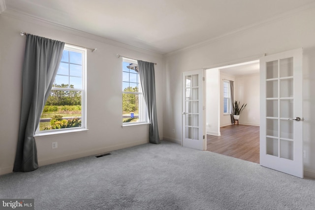 carpeted empty room with baseboards, visible vents, ornamental molding, and french doors