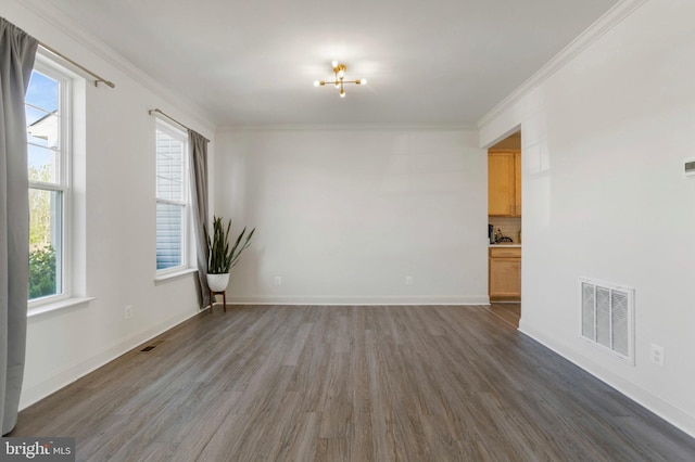 spare room featuring crown molding, visible vents, a healthy amount of sunlight, and wood finished floors