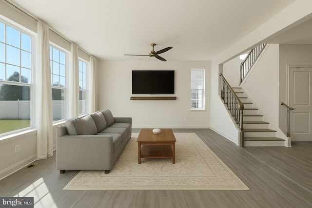living area with baseboards, a ceiling fan, stairs, and wood finished floors