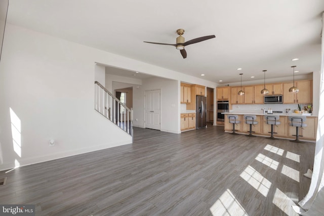 unfurnished living room with a ceiling fan, wood finished floors, stairway, baseboards, and recessed lighting