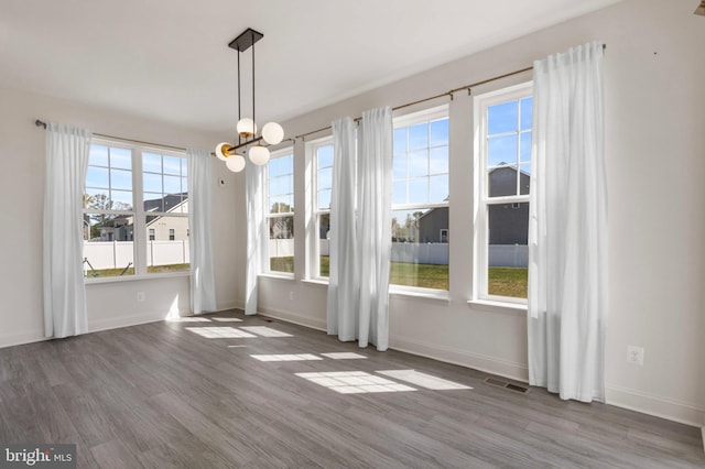 unfurnished dining area with baseboards, wood finished floors, and visible vents