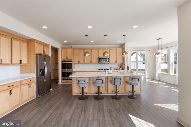 kitchen featuring light brown cabinetry, appliances with stainless steel finishes, decorative backsplash, and light countertops