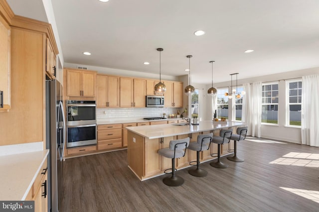 kitchen featuring light brown cabinetry, appliances with stainless steel finishes, dark wood finished floors, and light countertops