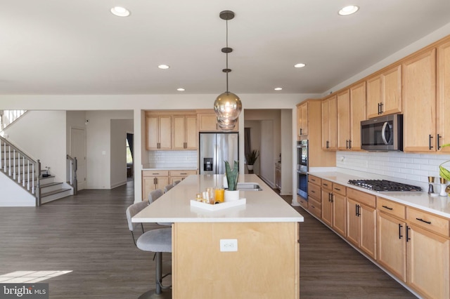 kitchen featuring light brown cabinets, a kitchen breakfast bar, light countertops, tasteful backsplash, and stainless steel appliances