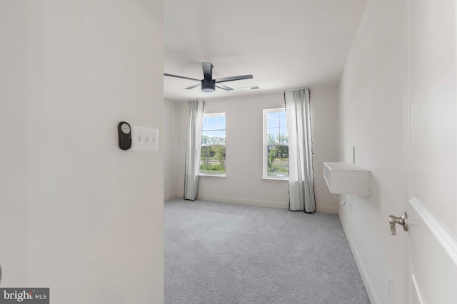 carpeted spare room with a ceiling fan and baseboards
