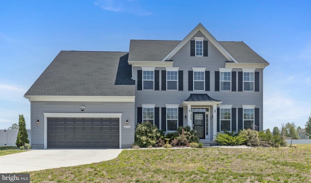 colonial house with an attached garage, driveway, and a front lawn