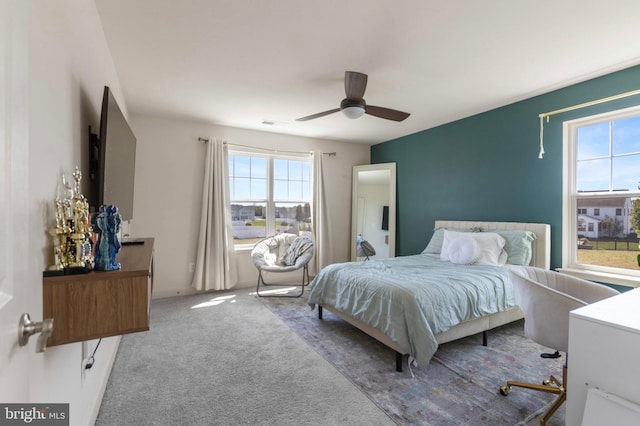carpeted bedroom featuring multiple windows, a ceiling fan, and visible vents