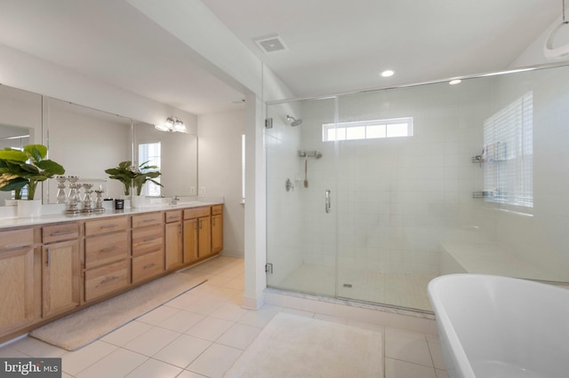full bathroom featuring plenty of natural light, tile patterned flooring, visible vents, and a soaking tub