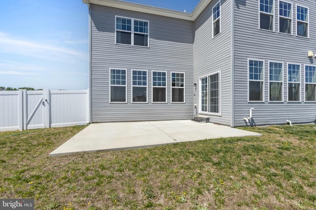back of property featuring a lawn, fence, a patio, and a gate