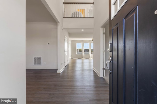 entryway featuring dark wood-style flooring, baseboards, visible vents, and a towering ceiling
