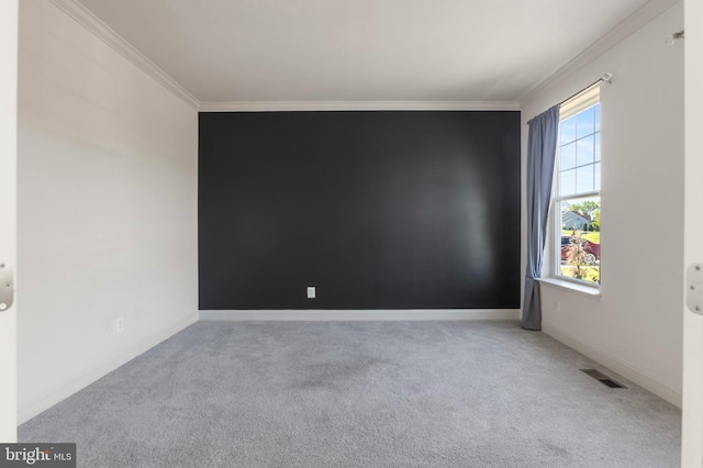 carpeted spare room with crown molding, baseboards, and visible vents