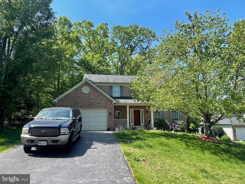 view of front facade with brick siding, a garage, a front lawn, and driveway