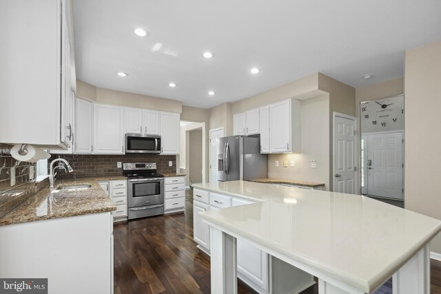 7883 Leroux Ln, Manassas, VA 20112 - kitchen with appliances with stainless steel finishes, a sink, a kitchen island, white cabinetry, and backsplash