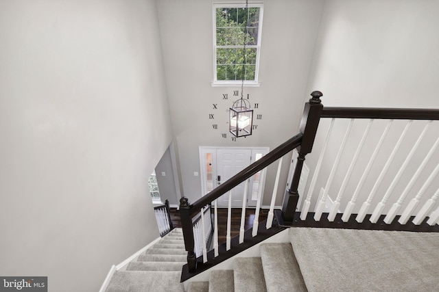 7883 Leroux Ln, Manassas, VA 20112 - stairs with carpet flooring, a chandelier, a towering ceiling, and baseboards