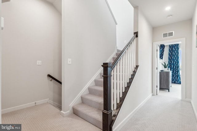 stairway with baseboards, visible vents, and carpet floors