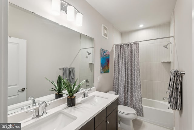 full bath with shower / bath combo, toilet, double vanity, and a sink