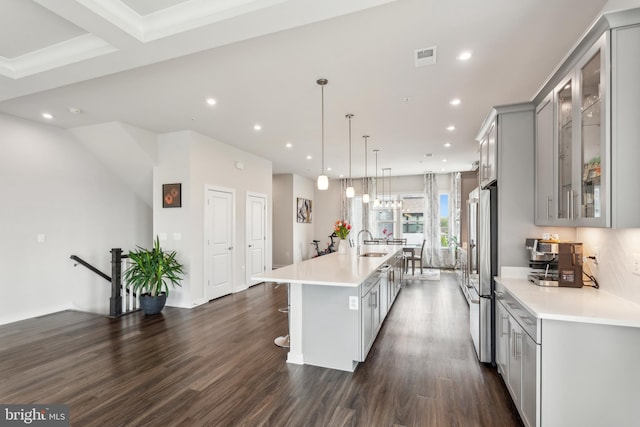 kitchen featuring gray cabinets, a breakfast bar, high quality fridge, light countertops, and a large island with sink
