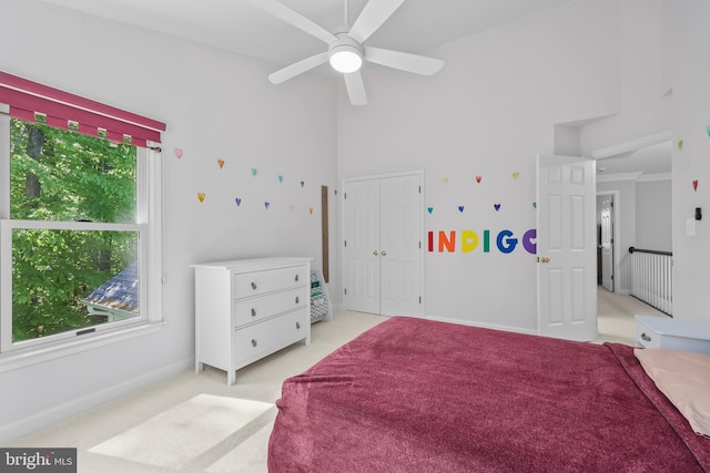 bedroom with baseboards, a high ceiling, a closet, and light colored carpet