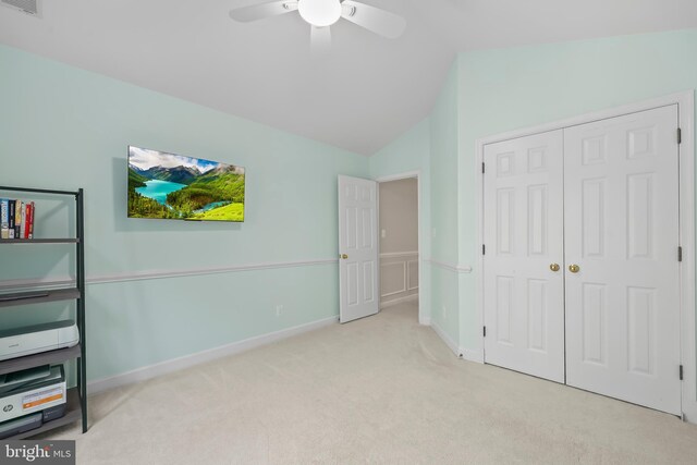 unfurnished bedroom with carpet floors, a closet, lofted ceiling, baseboards, and a ceiling fan
