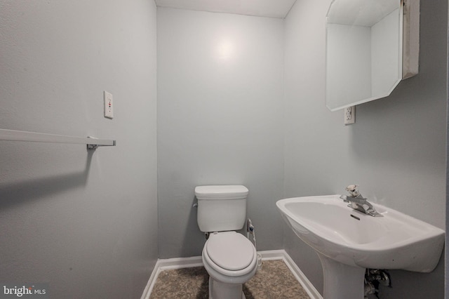 half bath with a sink, baseboards, and toilet