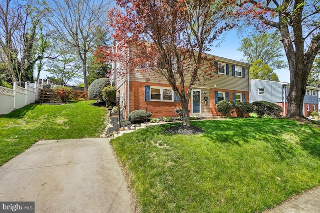 colonial-style house with brick siding, a front lawn, and fence