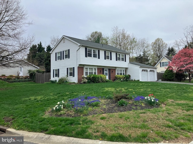 colonial home with brick siding, an attached garage, a front lawn, and fence