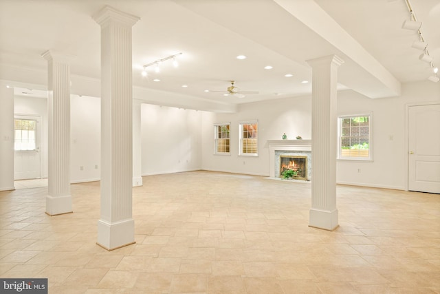 below grade area featuring light tile patterned floors, a fireplace, track lighting, baseboards, and ceiling fan