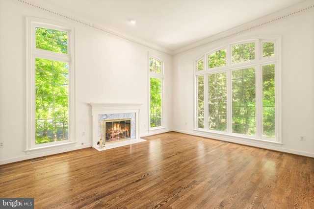 unfurnished living room featuring crown molding, a fireplace, baseboards, wood finished floors, and visible vents