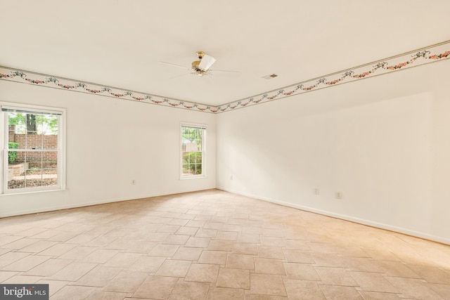 unfurnished room featuring a wealth of natural light, visible vents, baseboards, and a ceiling fan