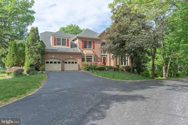 view of front of home with a front yard, brick siding, a garage, and aphalt driveway