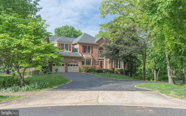 view of front facade with driveway, brick siding, and a garage