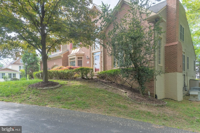 view of property exterior with a chimney and brick siding