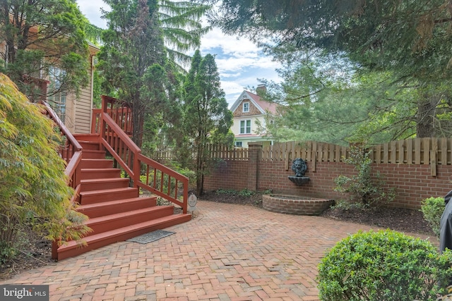 view of patio / terrace featuring fence and stairs