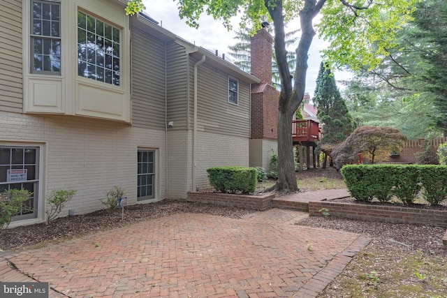 view of home's exterior featuring brick siding, a patio, and a chimney
