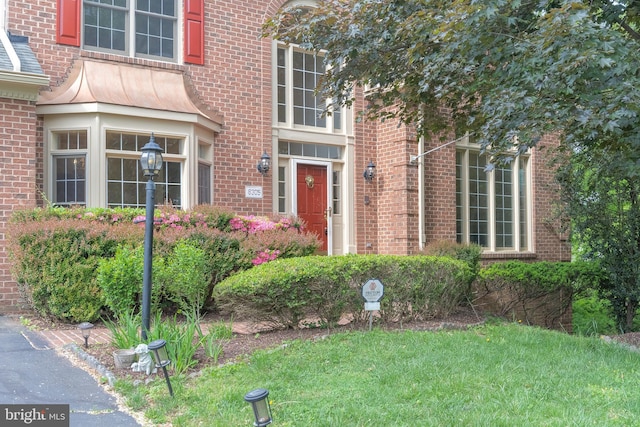 view of exterior entry featuring a yard and brick siding