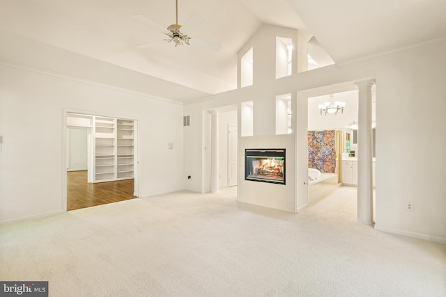 unfurnished living room featuring light colored carpet, a tiled fireplace, baseboards, ceiling fan with notable chandelier, and ornamental molding