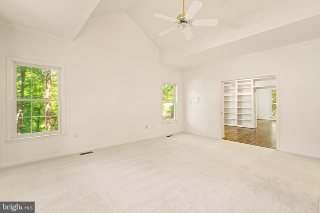 carpeted spare room with visible vents, ornamental molding, baseboards, high vaulted ceiling, and a ceiling fan