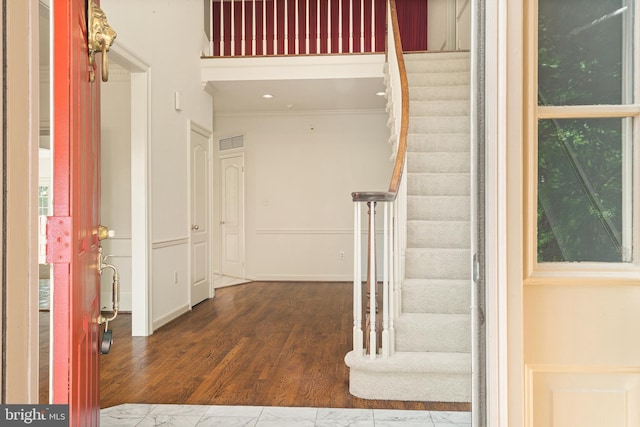 entrance foyer featuring visible vents, stairs, and crown molding