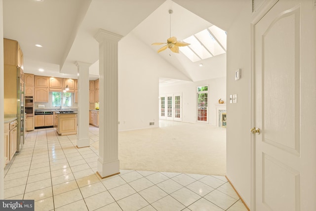 interior space featuring light tile patterned flooring, decorative columns, light carpet, and a healthy amount of sunlight