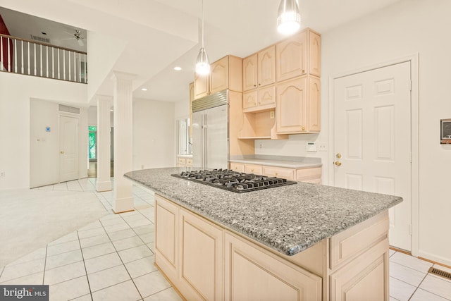 kitchen featuring a kitchen island, built in fridge, light tile patterned floors, stainless steel gas stovetop, and light brown cabinets